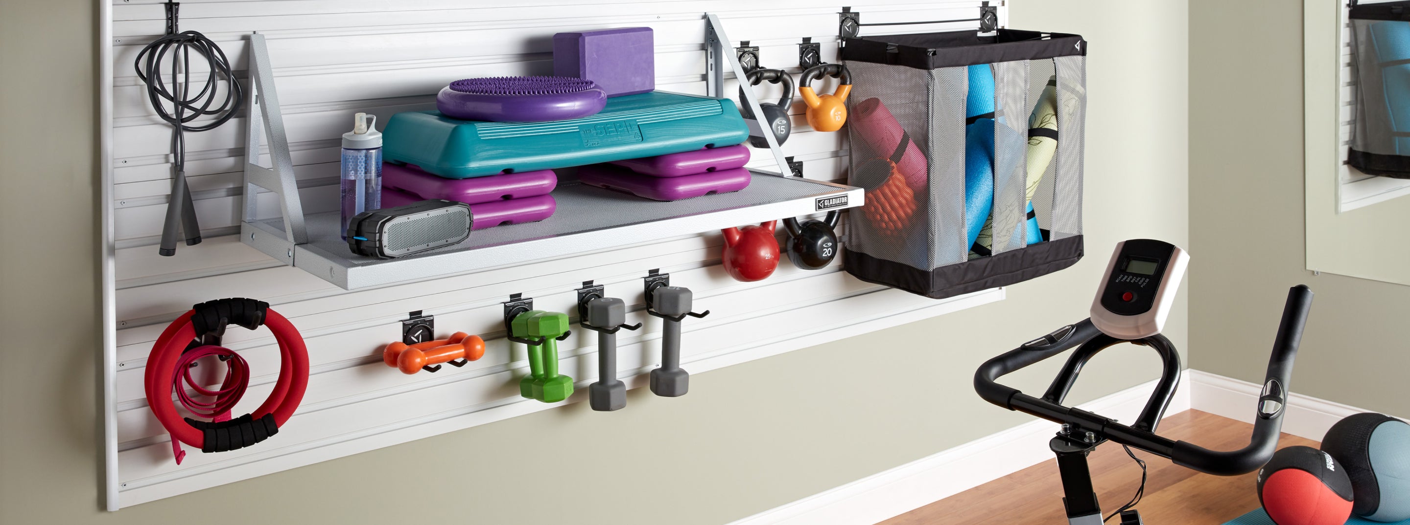 A series of Gladiator brand wall storage holding dumbbells, yoga mats, kettlebells, and other gym and fitness equipment.