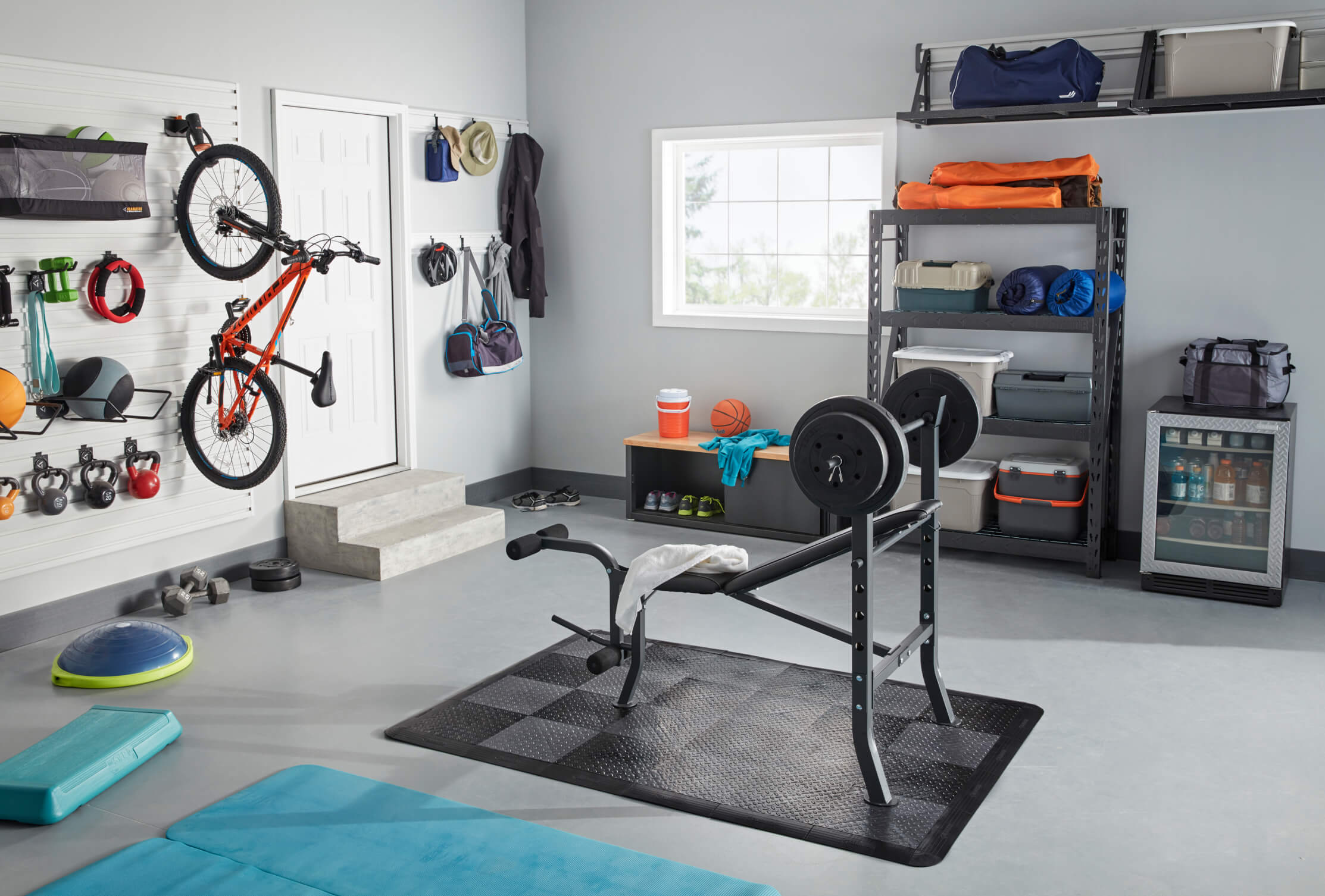 A finished garage used for exercise and projects featuring various Gladiator products, including wall shelves, cabinets and more.