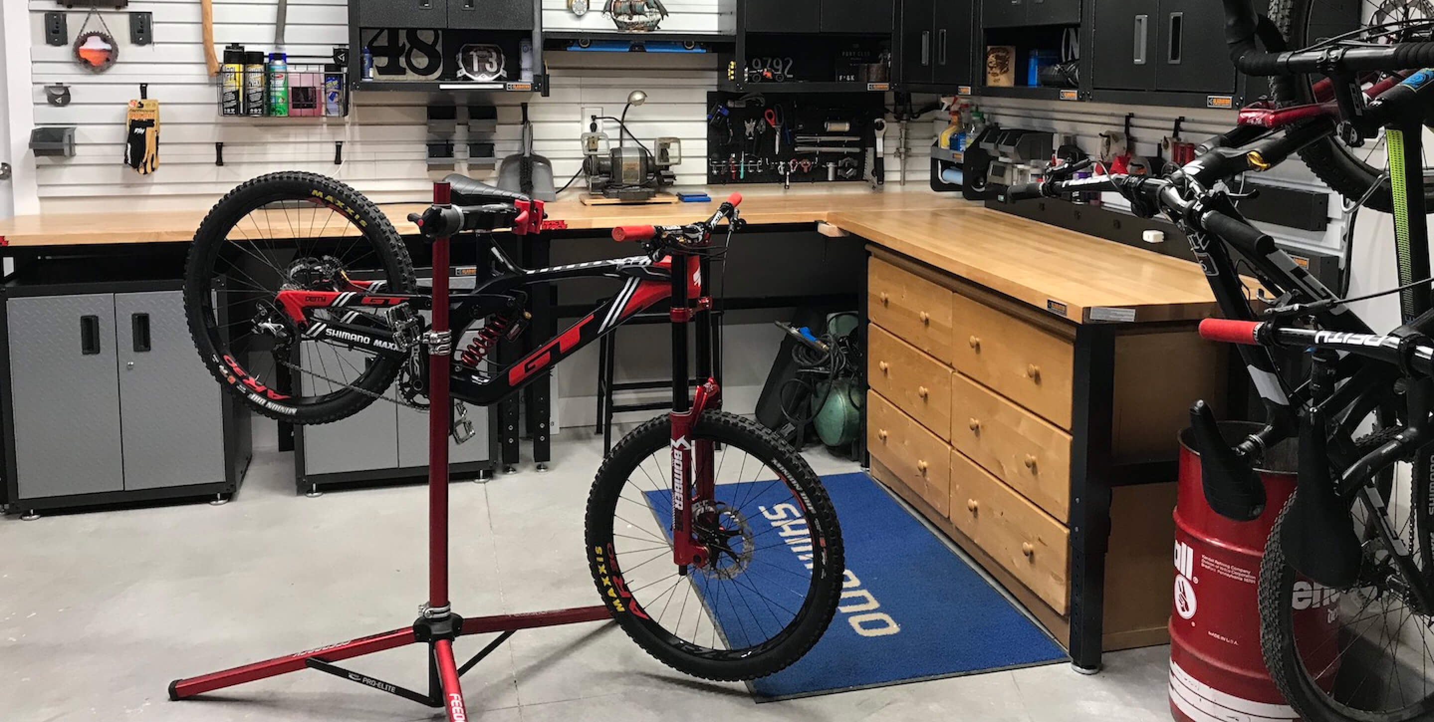 Several Gladiator brand workbenches and storage benches with a bike in the foreground.