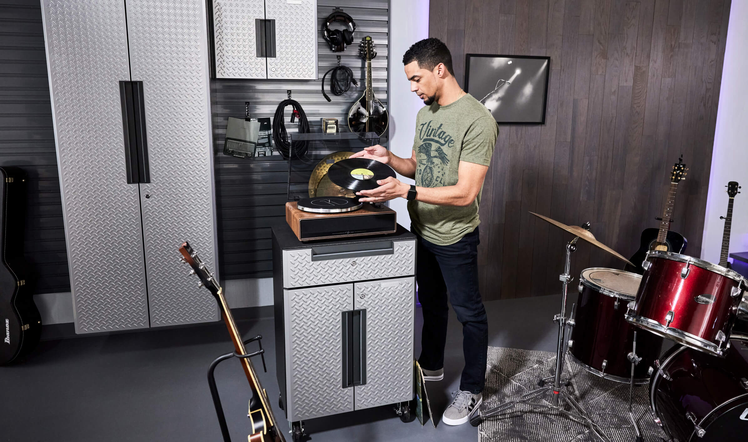 A person putting a vinyl record on a record player, with various Gladiator brand products in the surrounding area.