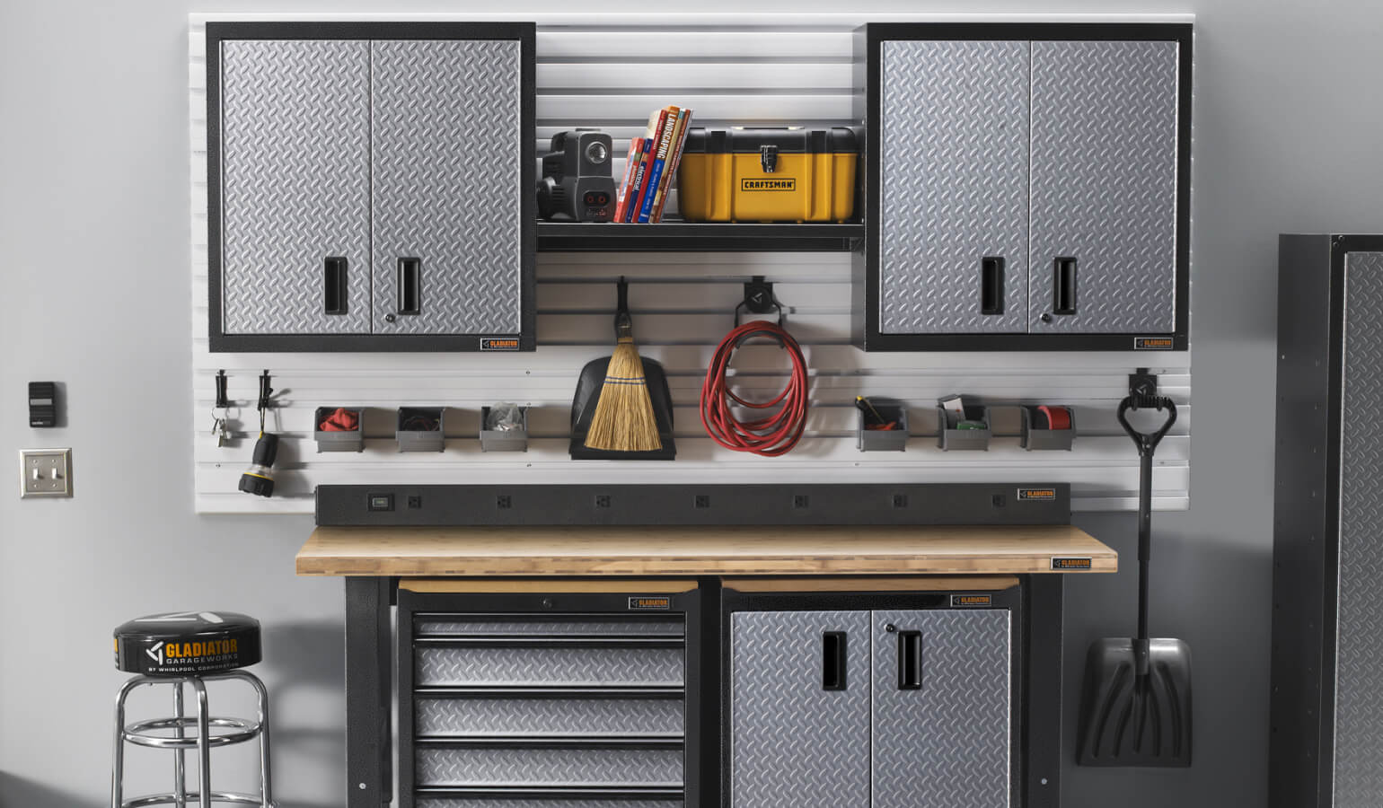A garage woodworking space, outfitted with various Gladiator brand wall cabinets, shelves, and workbenches.