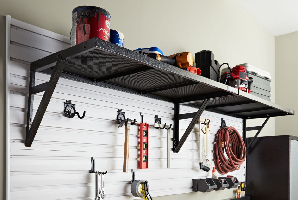 A Gladiator brand wall storage unit with various yard tools on it.