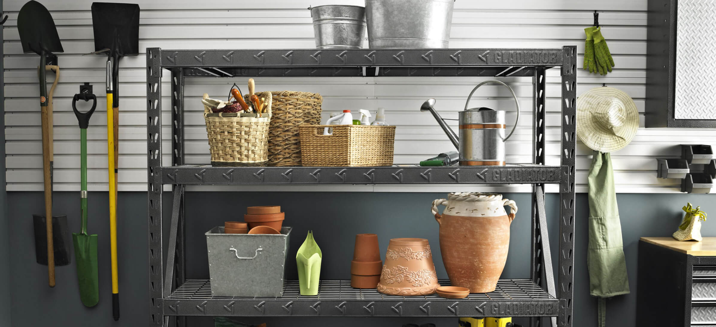 A Gladiator brand wall storage unit with various gardening implements.